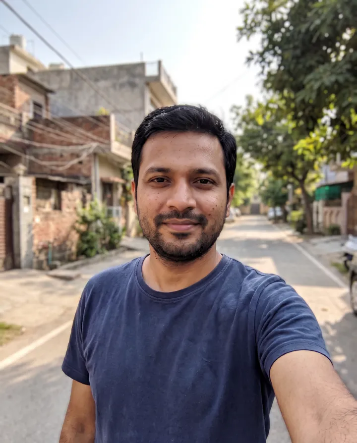 The same selfie with the parked car behind the man removed