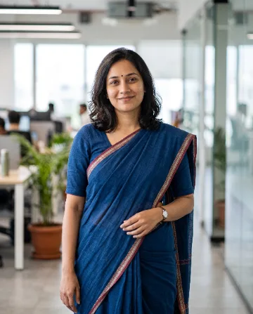 AI saree photo of the same woman in an indigo handloom cotton saree in a modern office