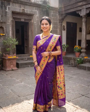 AI saree photo of the same woman in a purple Paithani silk saree with a gold peacock border, in a stone courtyard